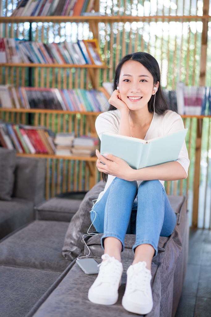 年轻女子在书店看书听音乐