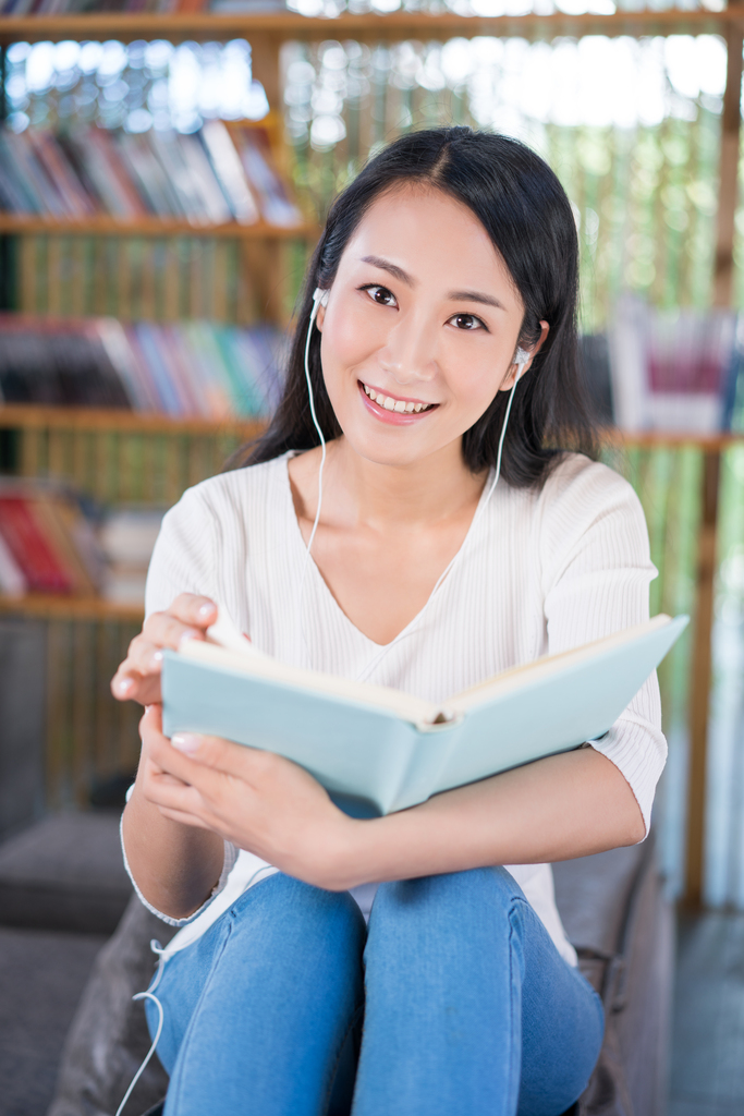 年轻女子在书店看书听音乐图片