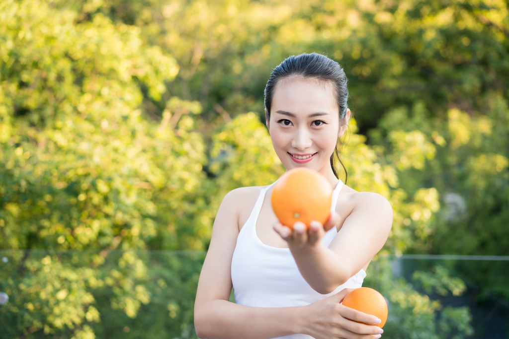 年轻女子手拿橙子