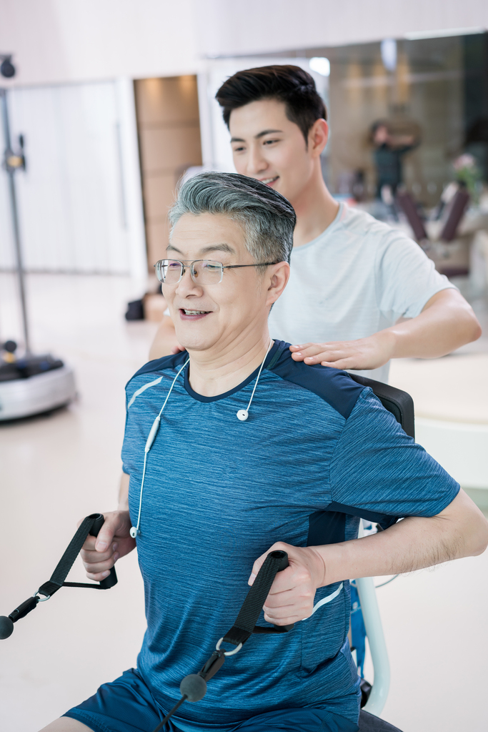 老年男子在私教指导下在健身房健身