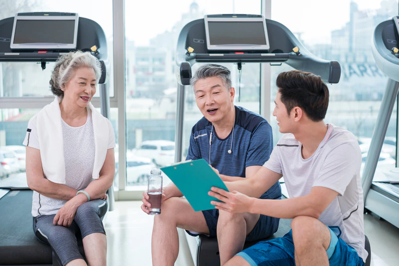 老年夫妇在私教的指导下在健身房健身