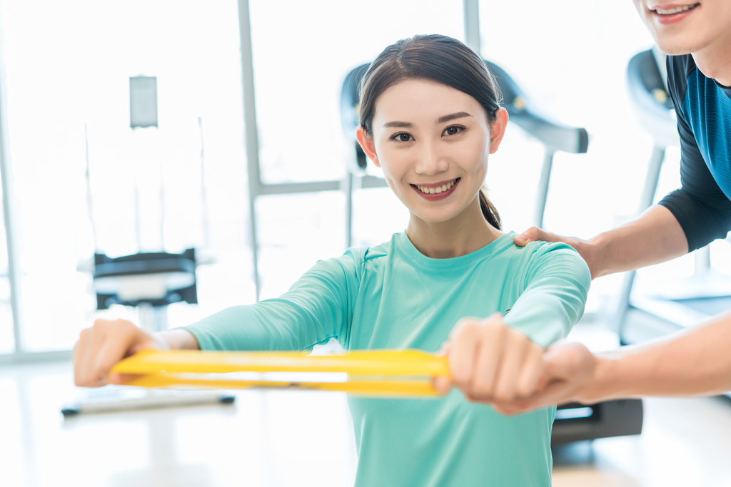 年轻女子在私教的指导下健身图片