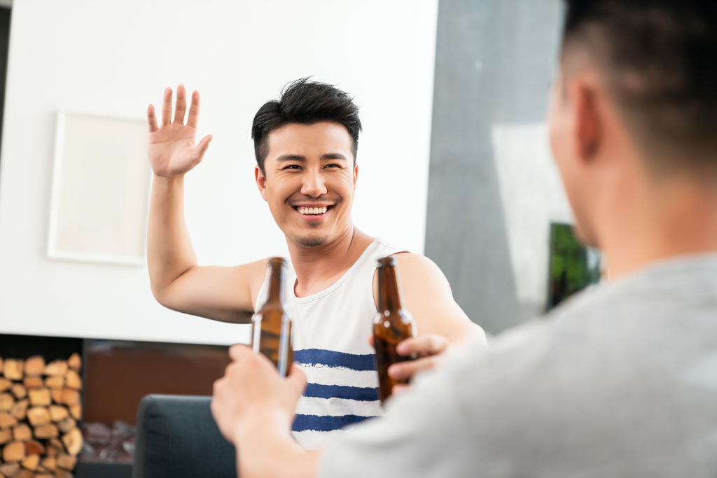 年轻男子坐在沙发喝啤酒图片