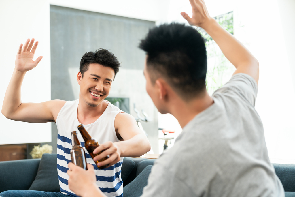年轻男子坐在沙发喝啤酒图片