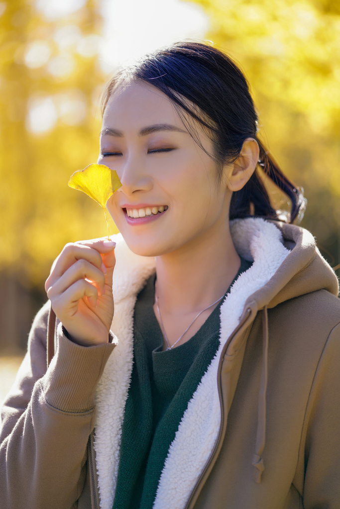 快乐的年轻女子手拿银杏叶图片