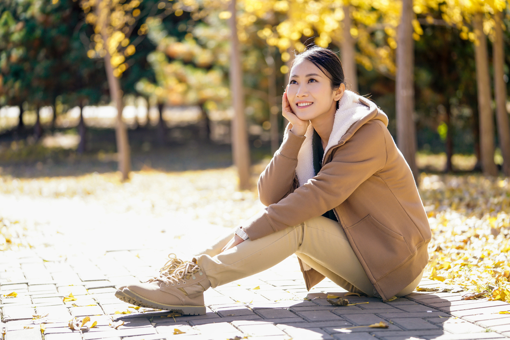 快乐的年轻女子托腮坐在路边图片