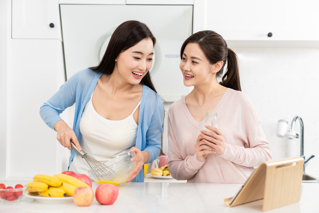 年轻女子在厨房边做饭边和朋友聊天