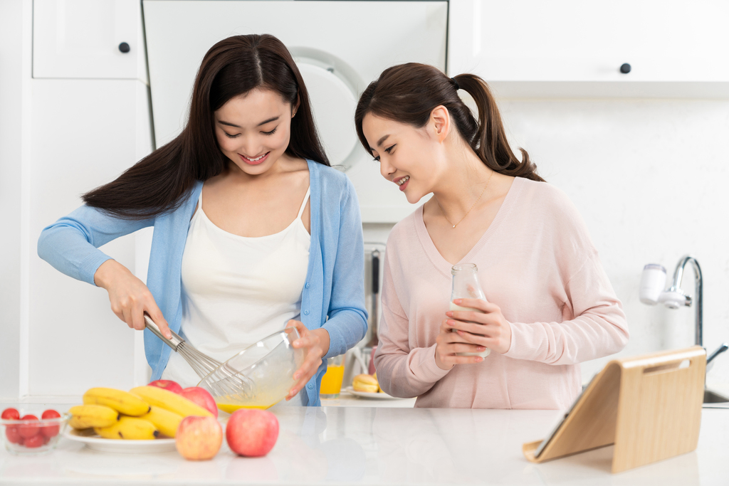 年轻女子在厨房边做饭边和朋友聊天