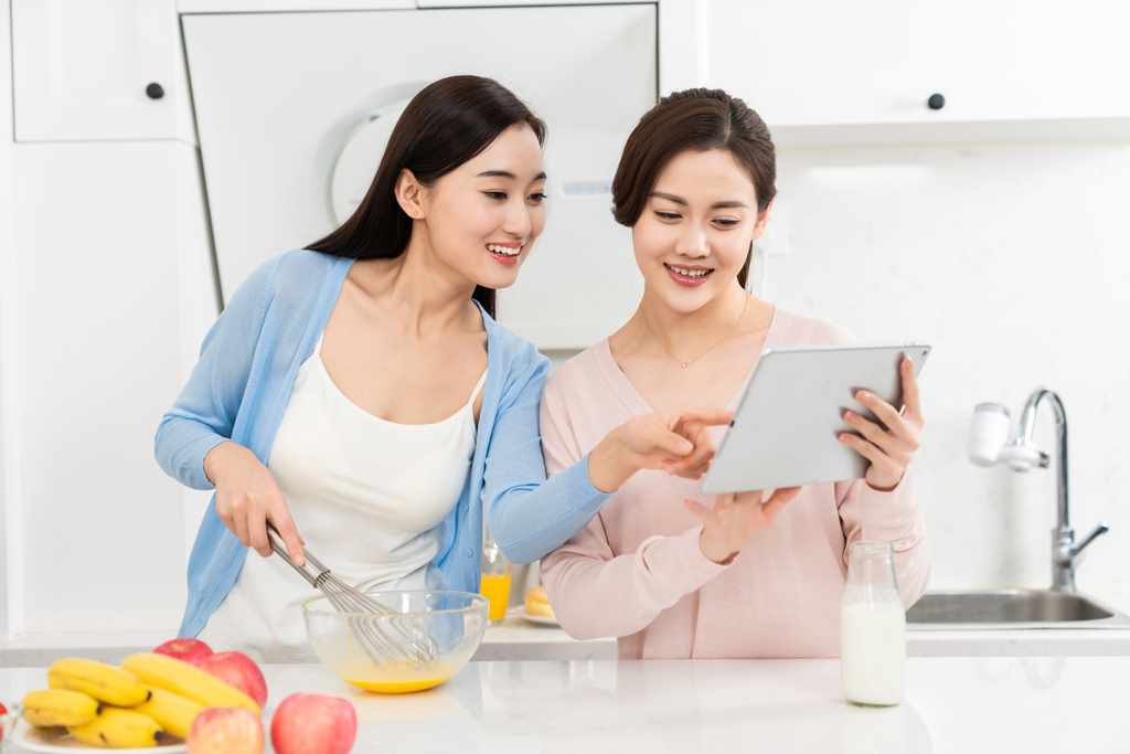 年轻女子在厨房边做饭边和朋友聊天图片