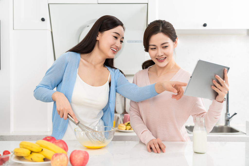 年轻女子在厨房边做饭边和朋友聊天