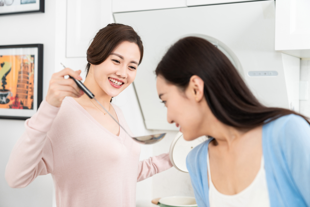 年轻女子在厨房边做饭边和朋友聊天