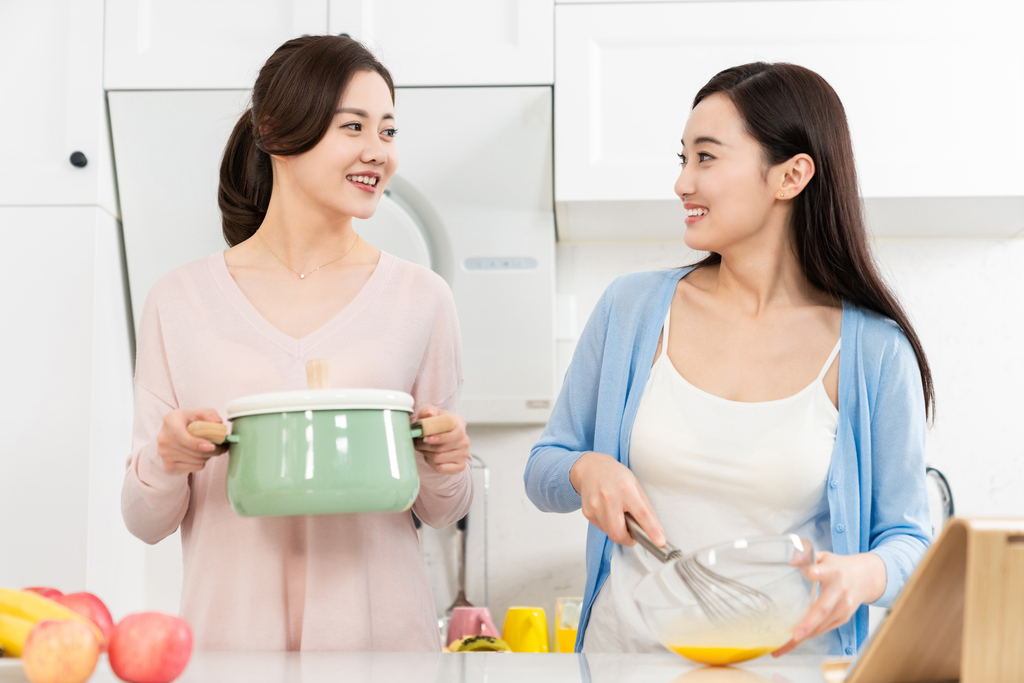 年轻女子在厨房边做饭边和朋友聊天图片