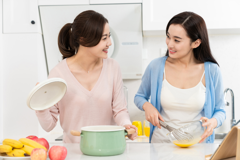 年轻女子在厨房边做饭边和朋友聊天图片