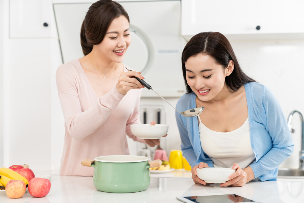 年轻女子在厨房边做饭边和朋友聊天