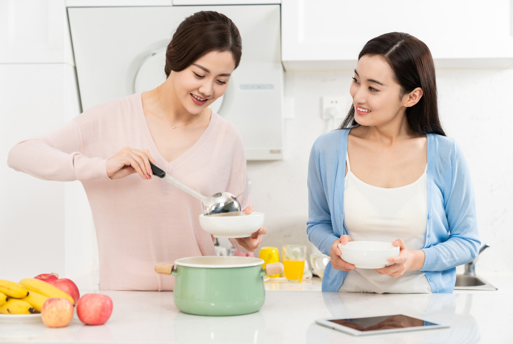 年轻女子在厨房边做饭边和朋友聊天图片