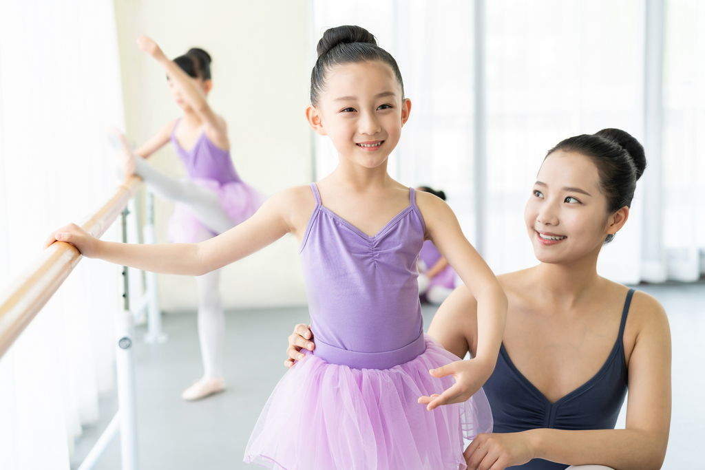年轻舞蹈老师教小女孩们跳芭蕾图片