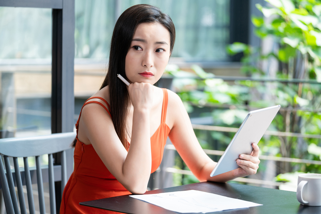 年轻女子看咖啡店使用平板电脑图片