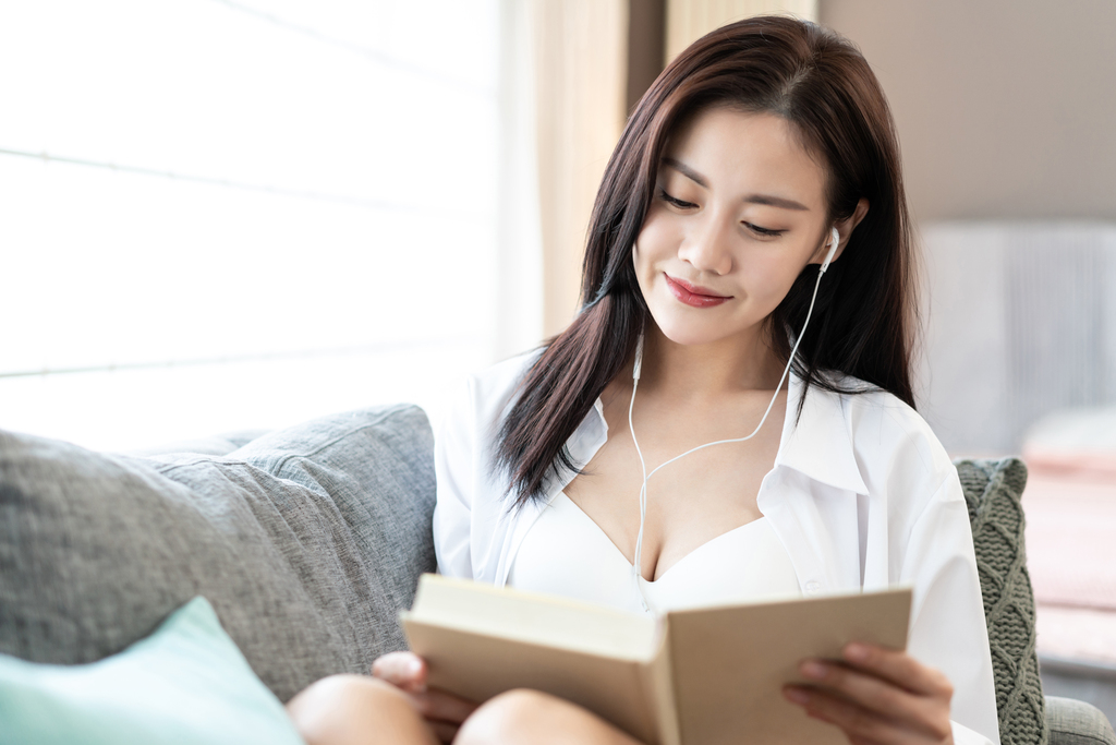 年轻女子在沙发上看书听音乐图片