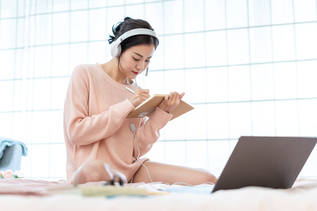 年轻女子在床上使用电脑图片