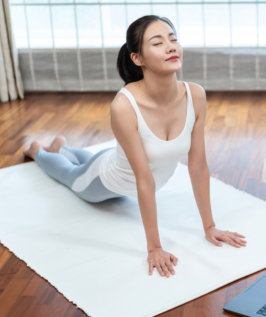 年轻女子看着笔记本电脑练习瑜伽图片