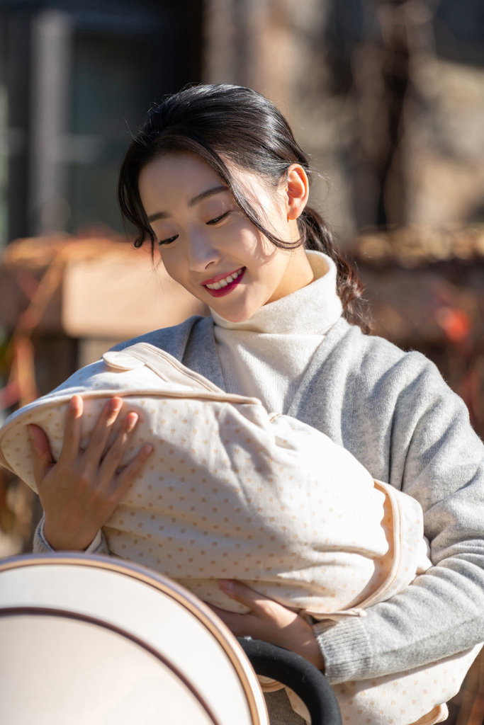 年轻的母亲抱着襁褓婴儿图片