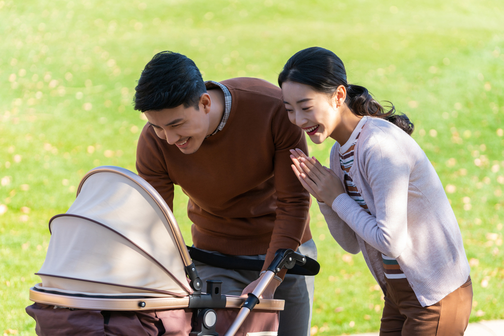 年轻夫妻推着婴儿车散步