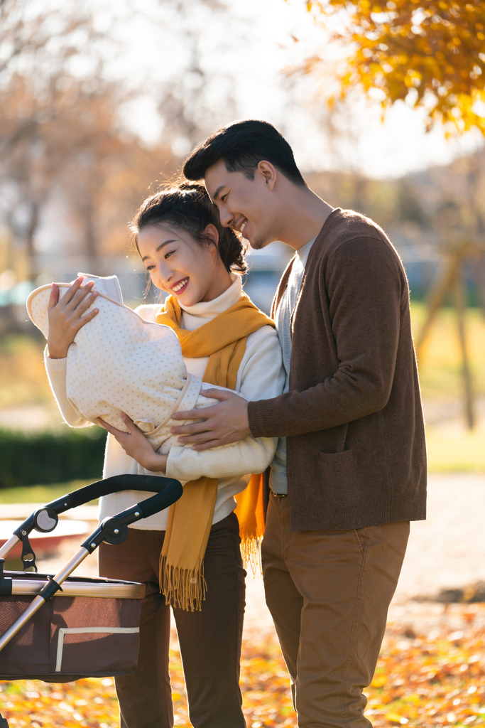 年轻夫妻推着婴儿车散步