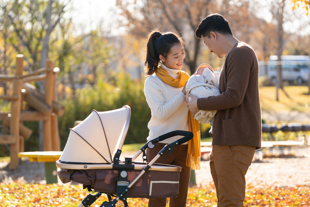 年轻夫妻推着婴儿车散步