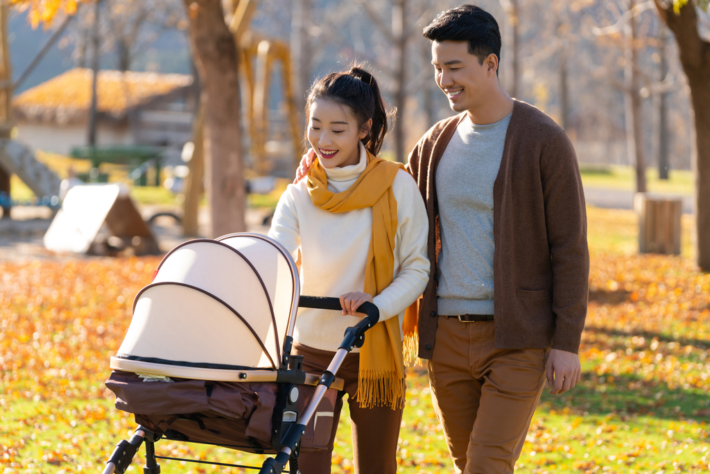 年轻夫妻推着婴儿车散步图片