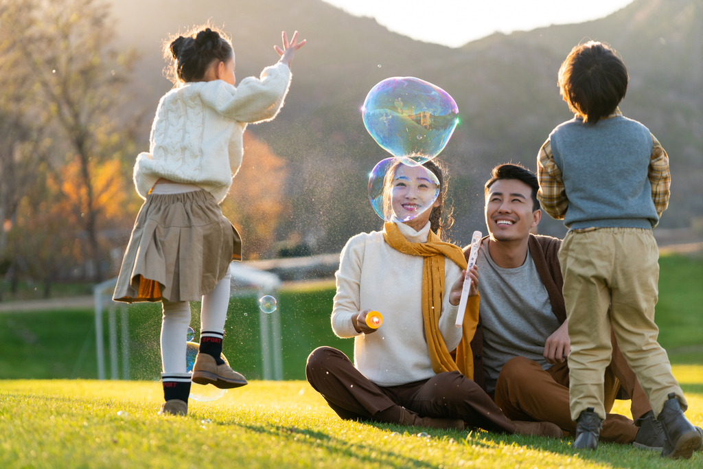 年轻夫妻和孩子们在草地上玩泡泡图片