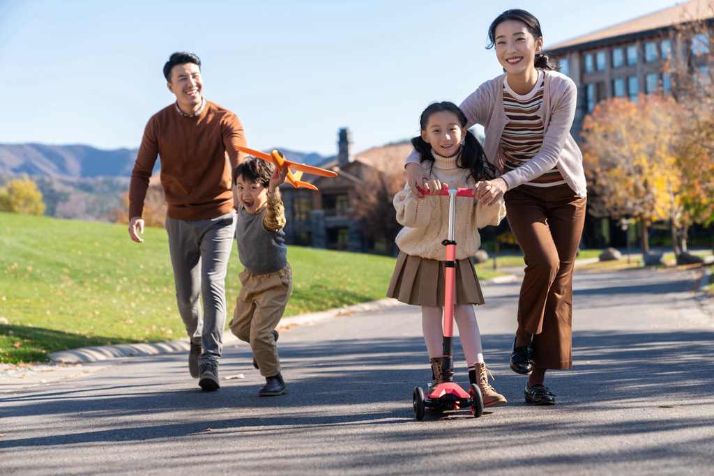 年轻夫妻带着孩子们在玩滑板车图片