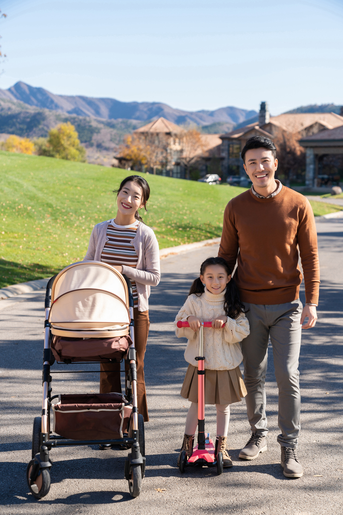 年轻夫妻推着婴儿车散步