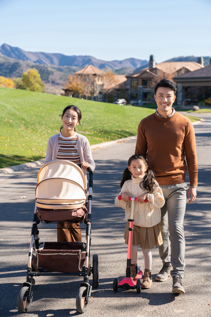 年轻夫妻推着婴儿车散步