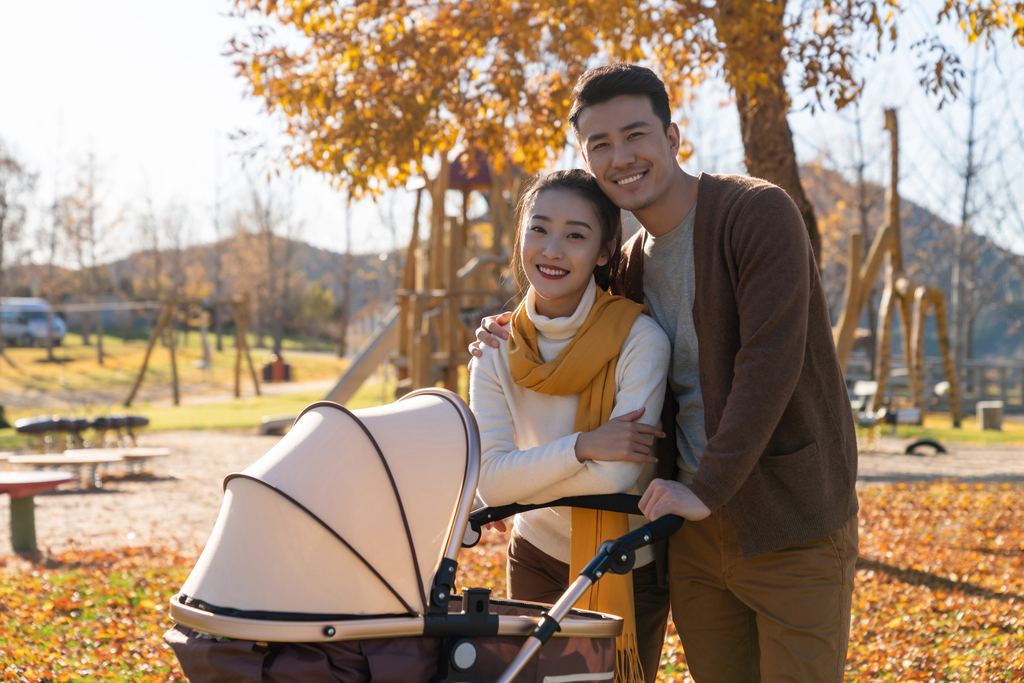 年轻夫妻推着婴儿车散步图片