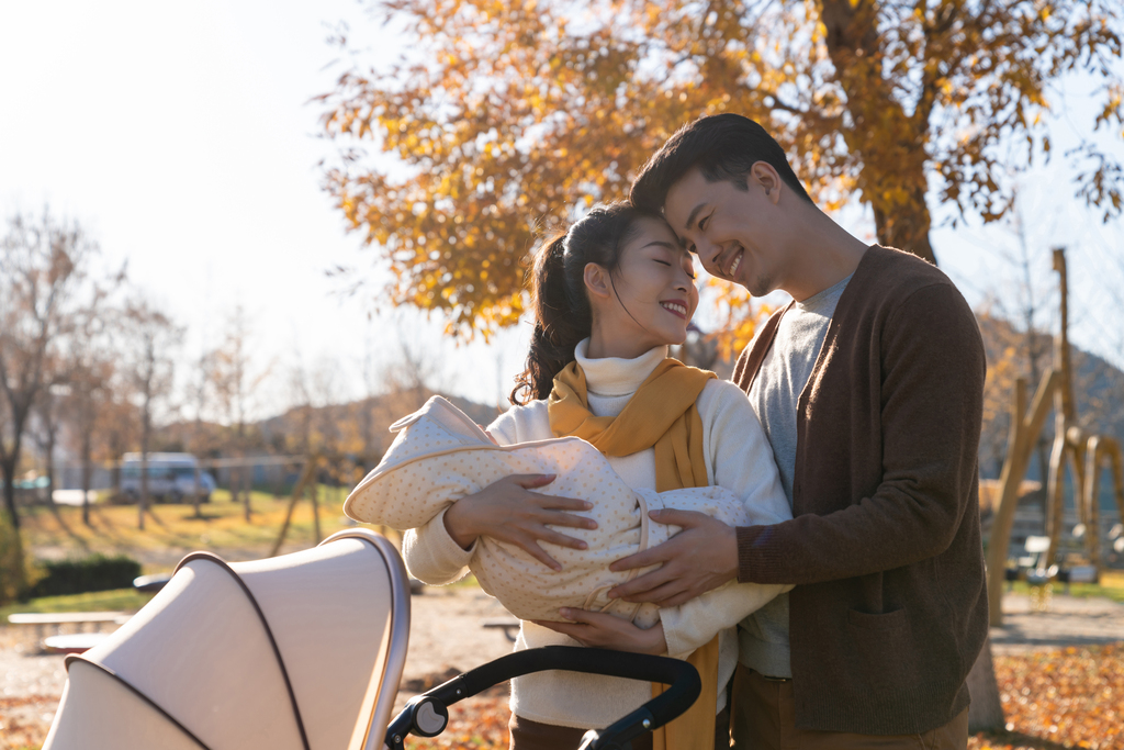 年轻夫妻推着婴儿车散步图片