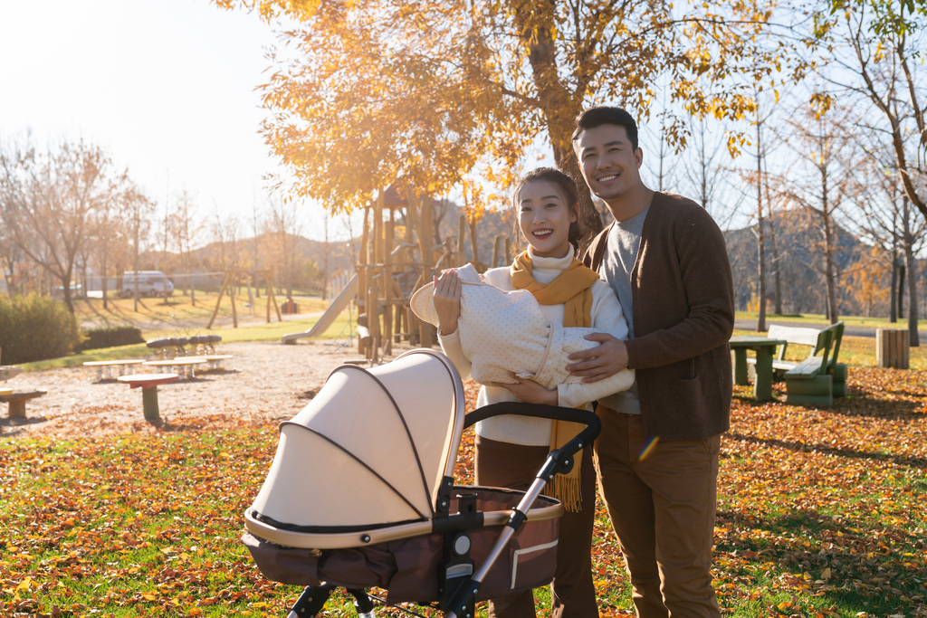 年轻夫妻推着婴儿车散步图片