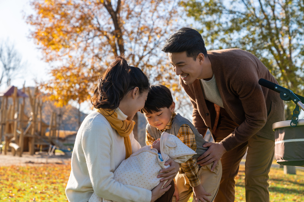 年轻家庭推着婴儿车散步图片