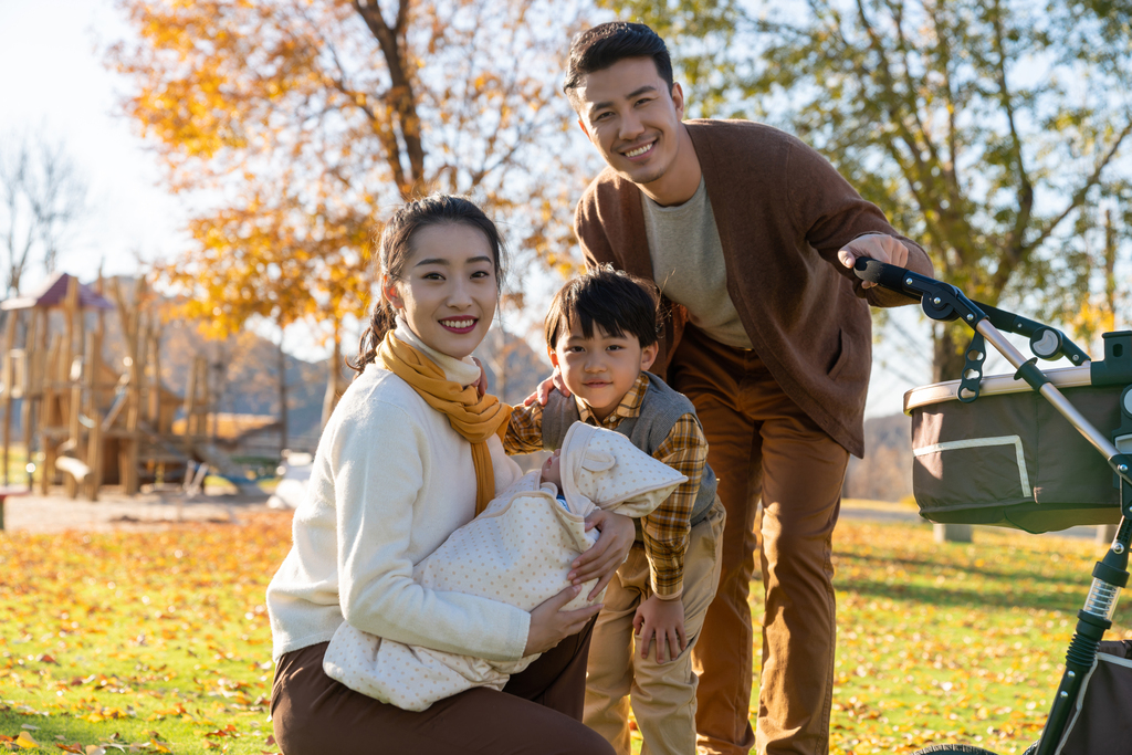 年轻家庭推着婴儿车散步图片