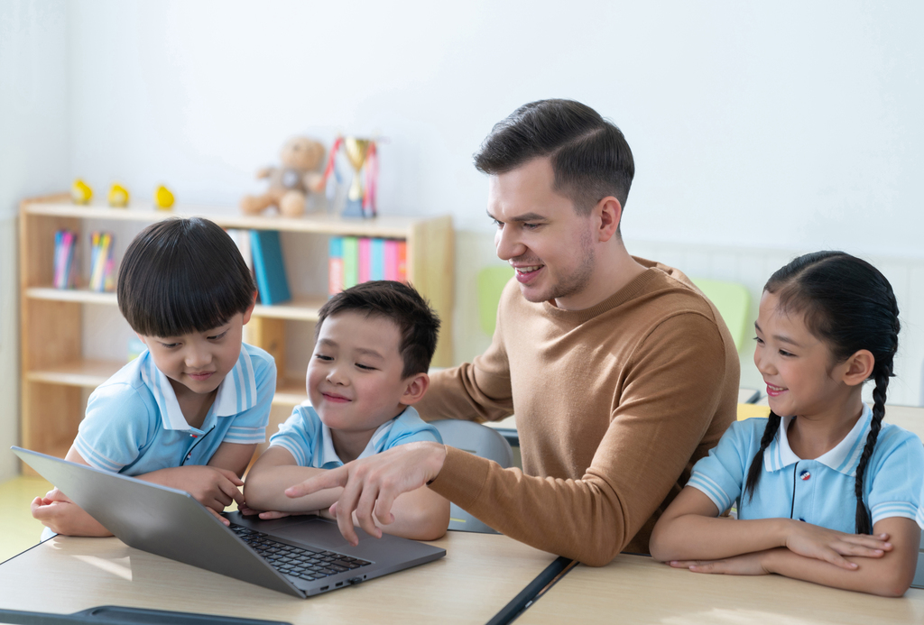 老师在课堂上辅导小学生用电脑图片