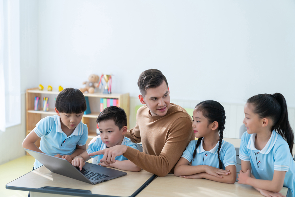 老师在课堂上辅导小学生用电脑图片