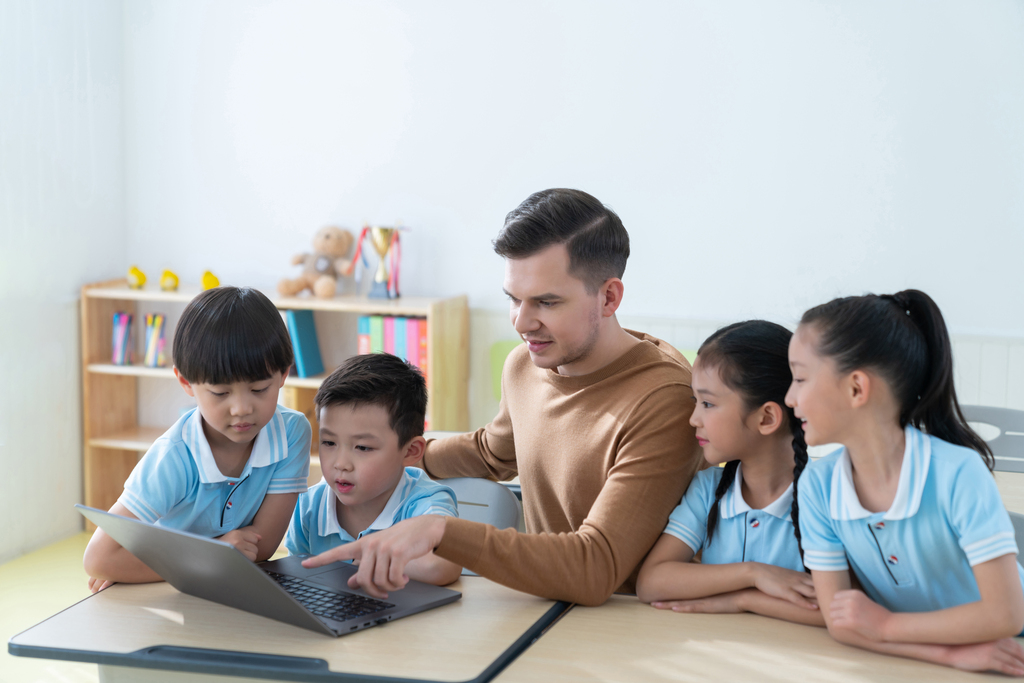 老师在课堂上辅导小学生用电脑图片