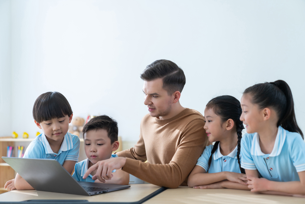 老师在课堂上辅导小学生用电脑图片