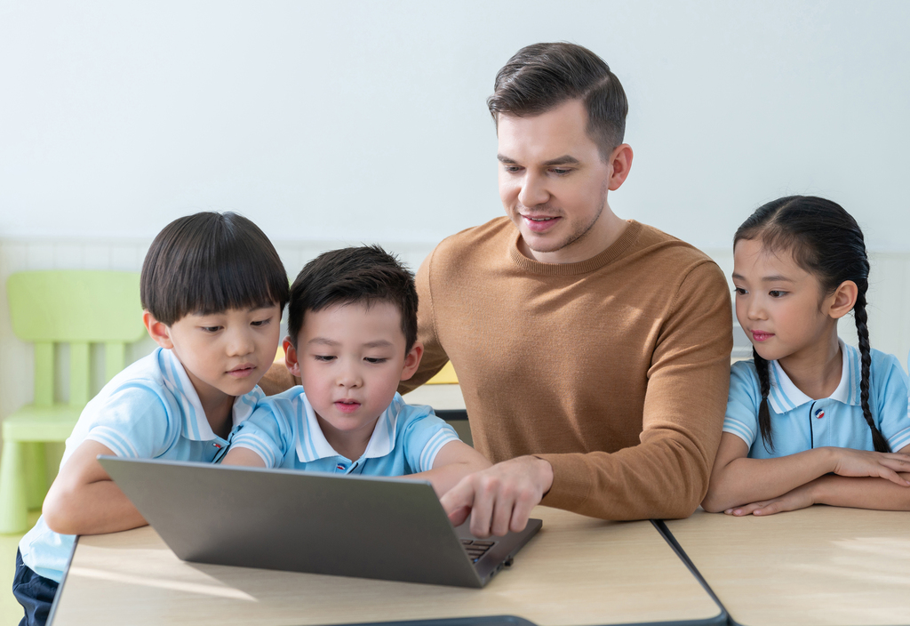 老师在课堂上辅导小学生用电脑图片