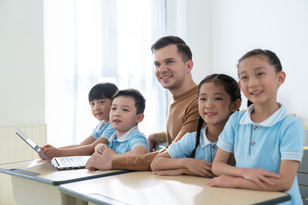 老师在课堂上辅导小学生用电脑图片