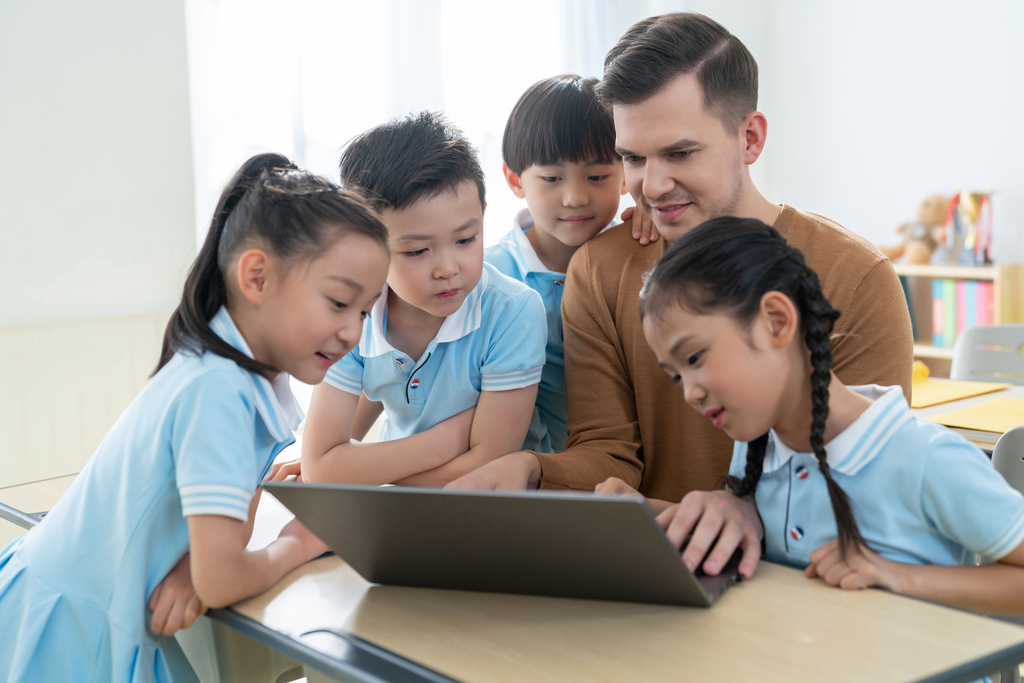 老师在课堂上辅导小学生用电脑图片