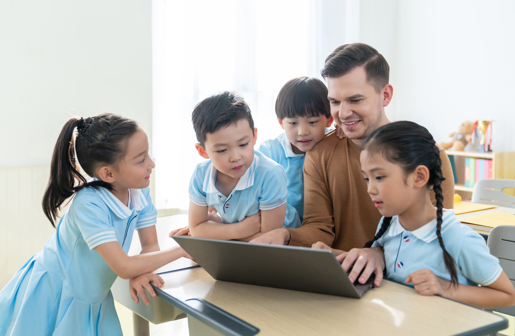 老师在课堂上辅导小学生用电脑图片