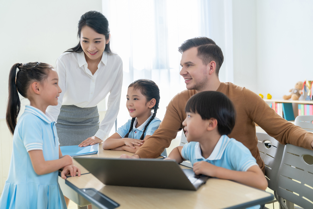 老师在课堂上辅导小学生用电脑图片