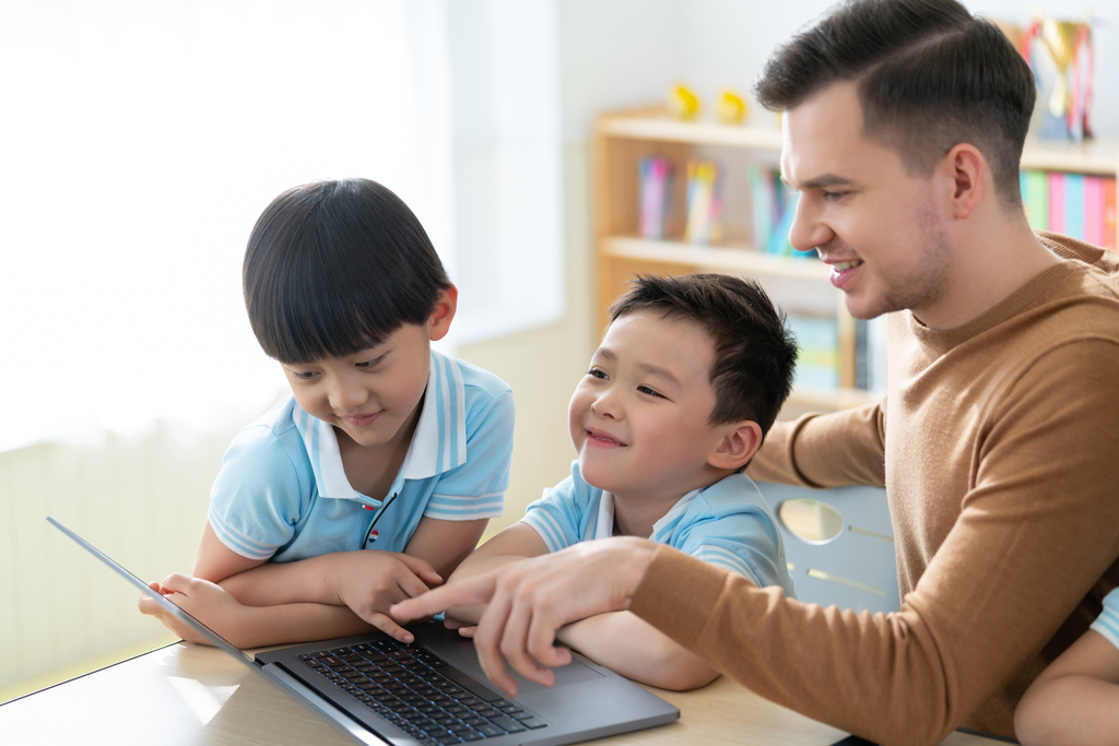 老师在课堂上辅导小学生用电脑图片