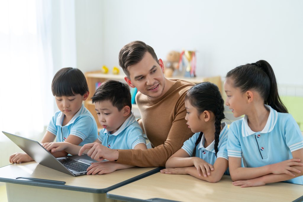 老师在课堂上辅导小学生用电脑图片