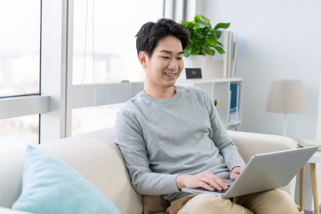 年轻男子在沙发上使用笔记本电脑图片